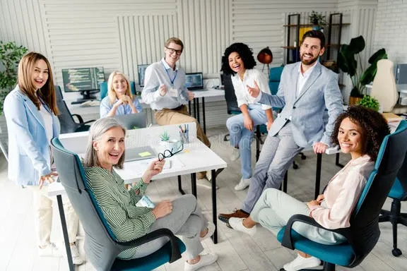 A diverse team of coworkers smiling while celebrating a birthday in an office breakroom