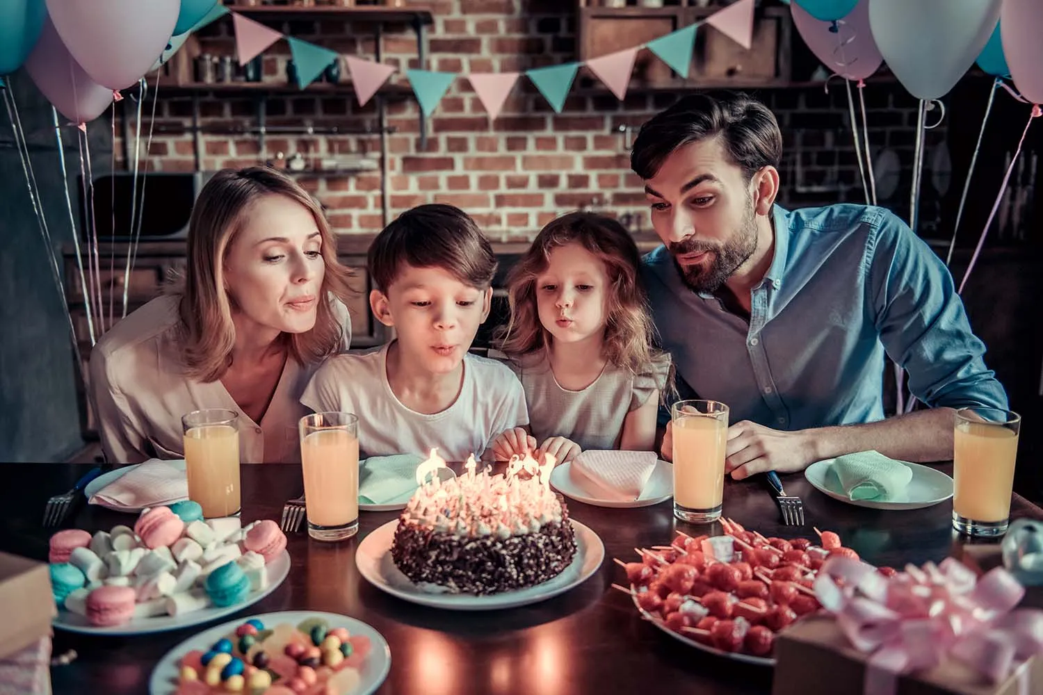 A multi-generational family sitting together around a birthday cake with lit candles
