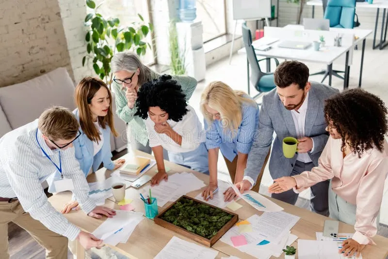 A group of coworkers signing a large card for a colleague