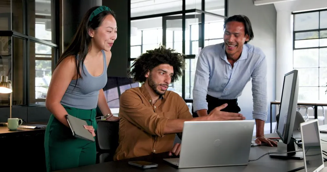 A group of coworkers collaborating around a laptop, representing the team taking on extra work for a grieving peer.